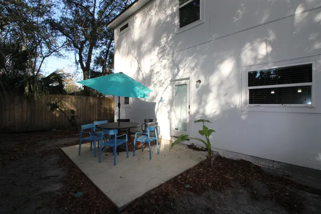 a view of a patio with table and chairs under an umbrella with wooden fence
