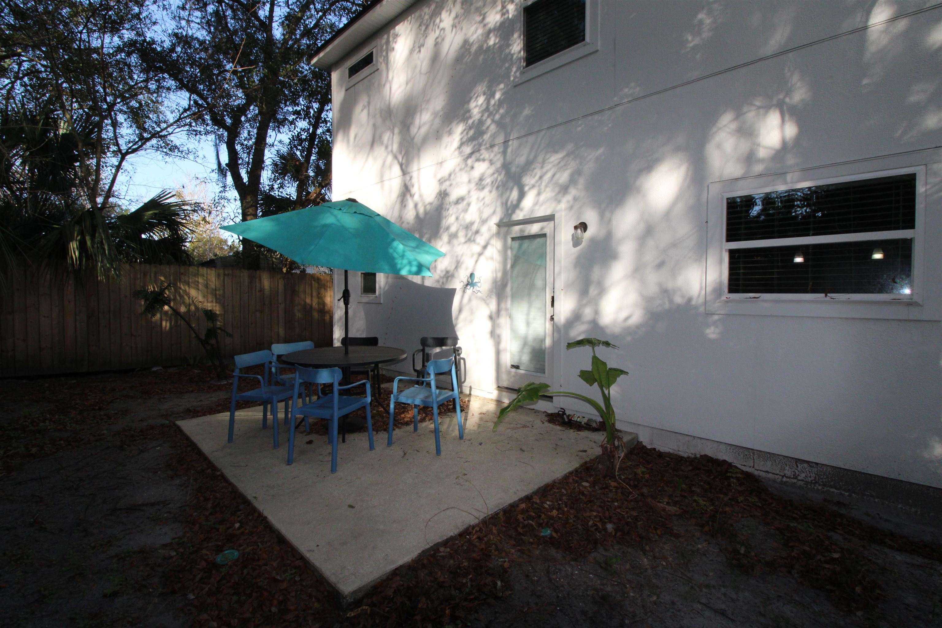 241 Columbus Street St. Augustine, FL 32084 - Photo 47 of 47 a view of a patio with table and chairs under an umbrella with wooden fence