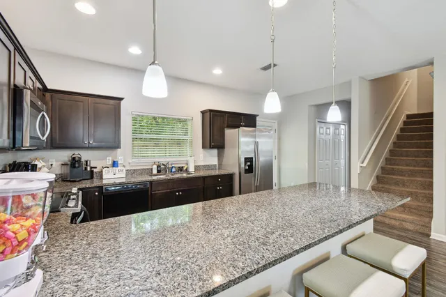a kitchen with stainless steel appliances granite countertop a sink refrigerator and cabinets
