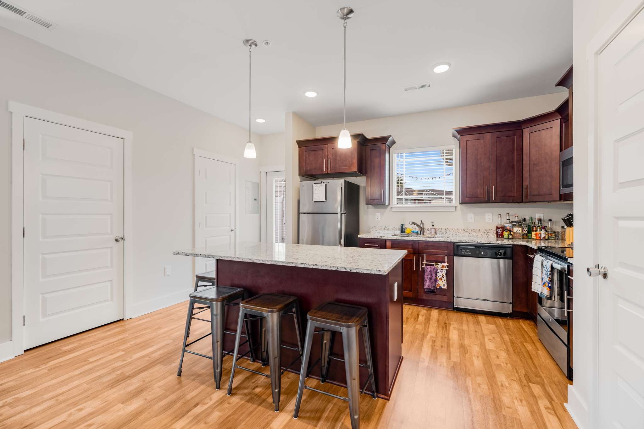 7024 Magnolia Crossings Spring Hill, TN 37174 - Photo 8 of 40 a kitchen with stainless steel appliances granite countertop a kitchen island a stove a refrigerator a sink a dining table and chairs with wooden floor