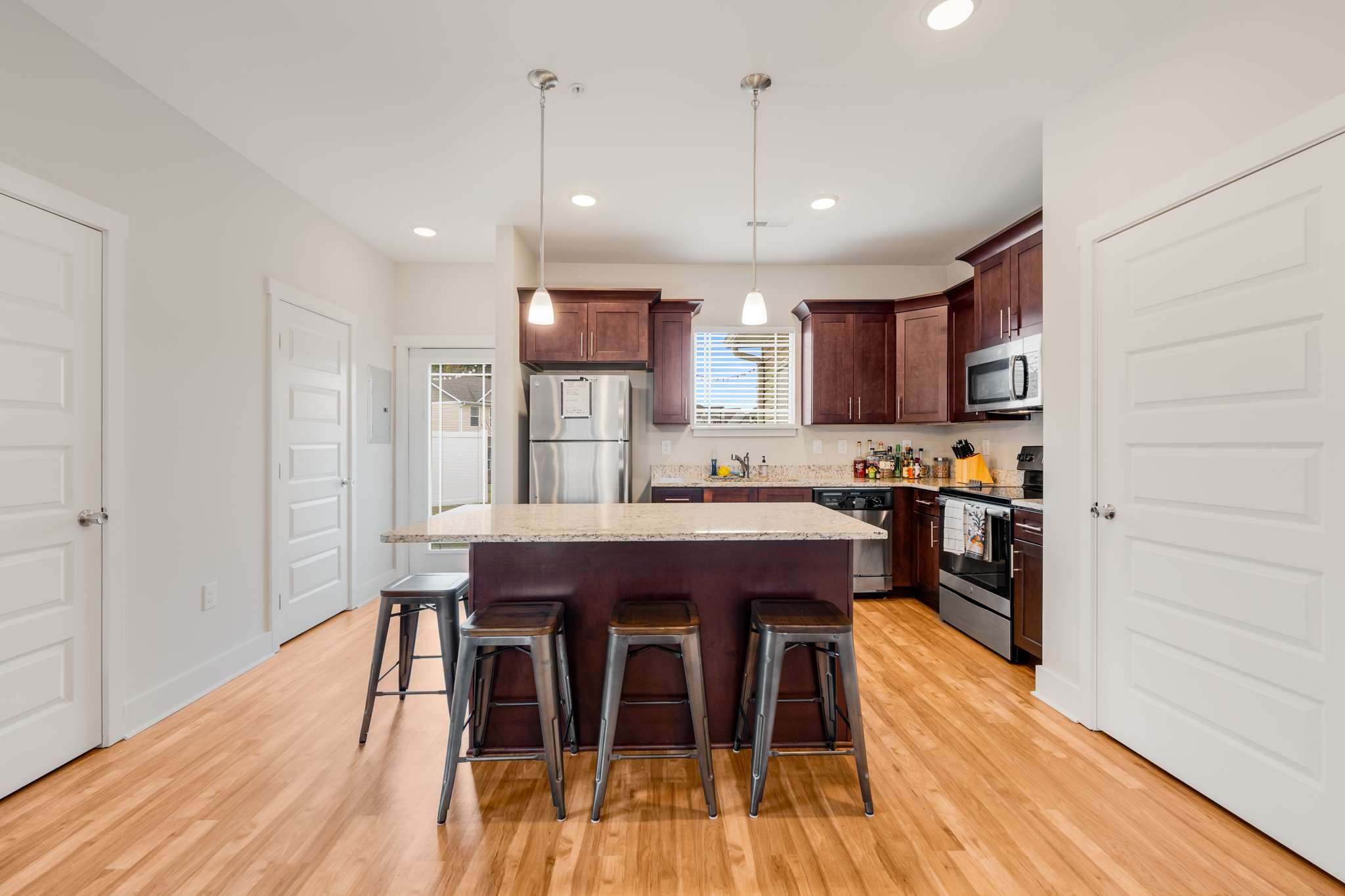 7024 Magnolia Crossings Spring Hill, TN 37174 - Photo 9 of 40 a kitchen with stainless steel appliances kitchen island granite countertop a table chairs sink and cabinets