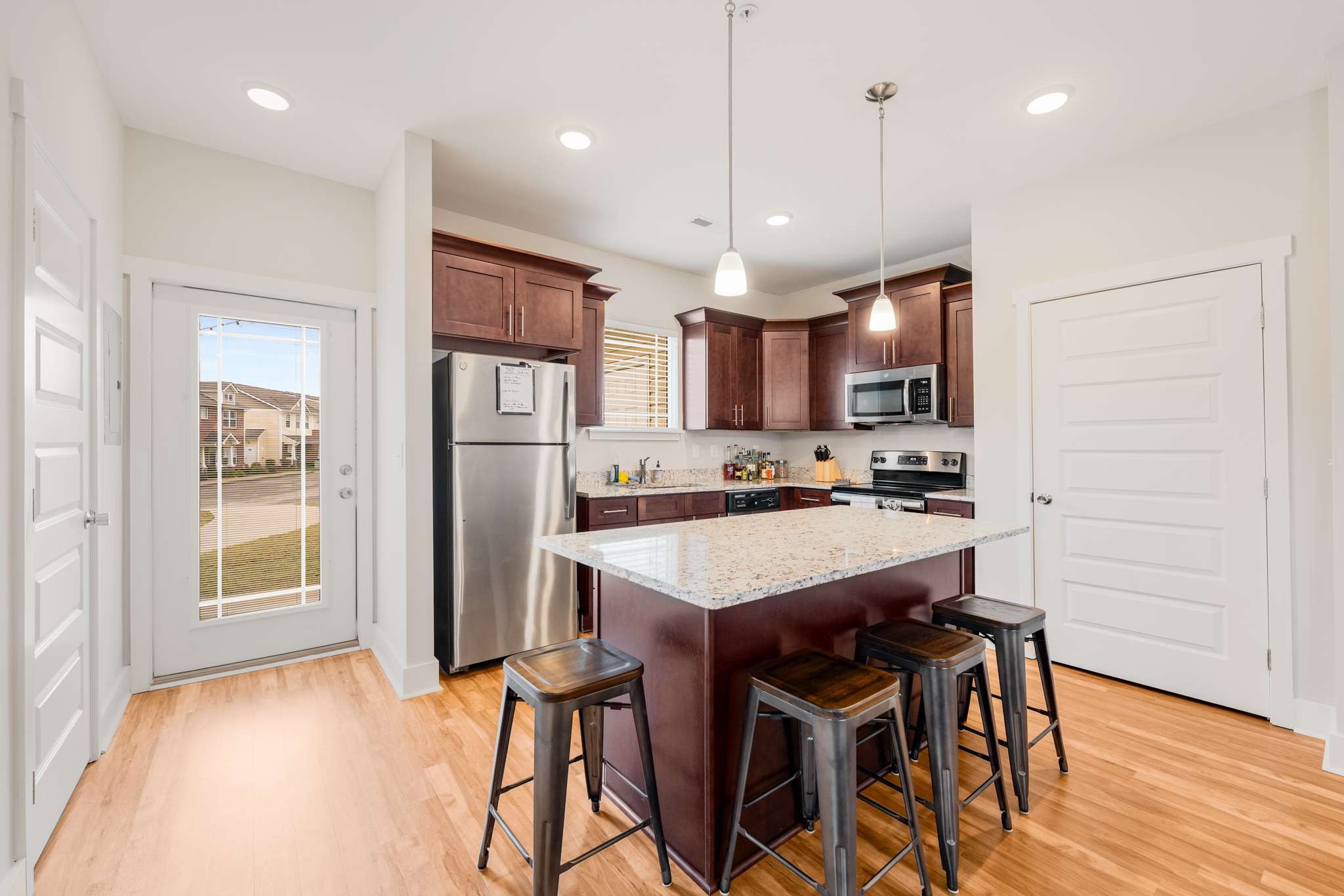 7024 Magnolia Crossings Spring Hill, TN 37174 - Photo 10 of 40 a kitchen with stainless steel appliances granite countertop a refrigerator a sink dishwasher a stove a dining table and chairs with wooden floor