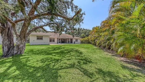 a view of a white house with a big yard and a large tree