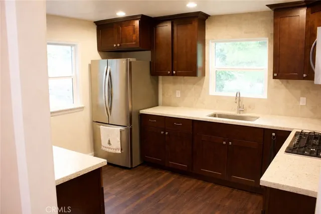 a kitchen with stainless steel appliances a refrigerator a sink a stove a microwave and wooden cabinets