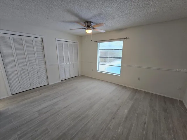 an empty room with wooden floor cabinet and windows