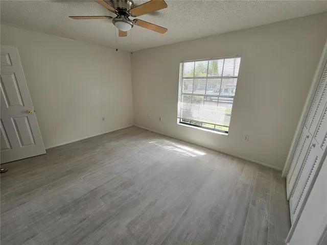 an empty room with a window and a ceiling fan