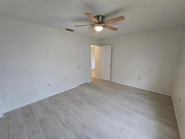an empty room with wooden floor and ceiling fan