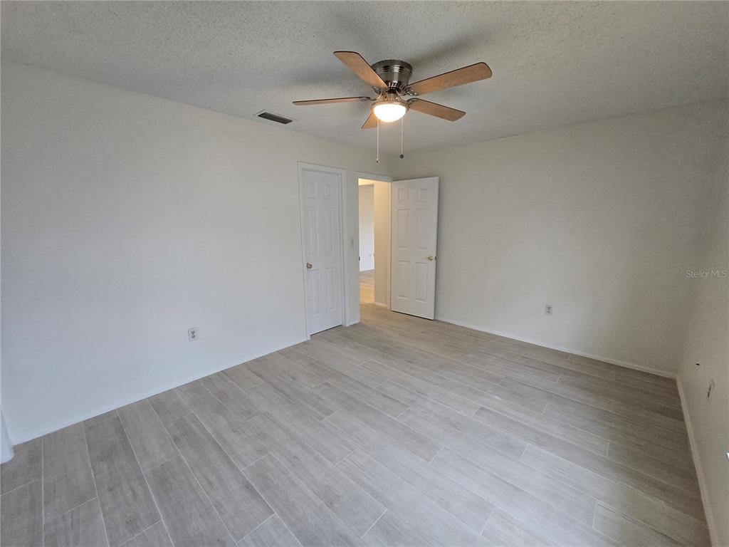11127 Peppertree Lane Port Richey, FL 34668 - Photo 17 of 25 an empty room with wooden floor and ceiling fan