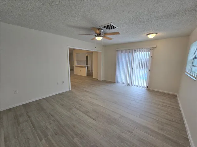 an empty room with wooden floor ceiling fan and windows