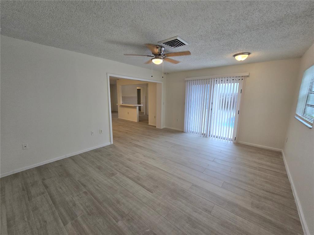 11127 Peppertree Lane Port Richey, FL 34668 - Photo 23 of 25 an empty room with wooden floor ceiling fan and windows