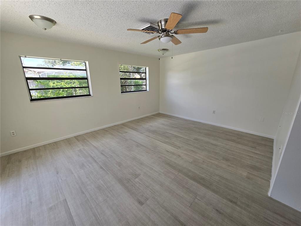 11127 Peppertree Lane Port Richey, FL 34668 - Photo 8 of 25 an empty room with wooden floor chandelier fan and windows