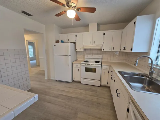 a kitchen with cabinets a sink and white stainless steel appliances