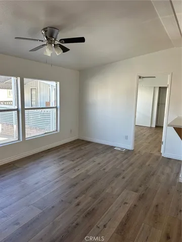 an empty room with wooden floor fan and windows