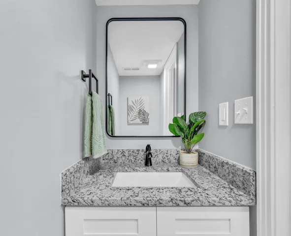 a bathroom with a granite countertop sink and a mirror