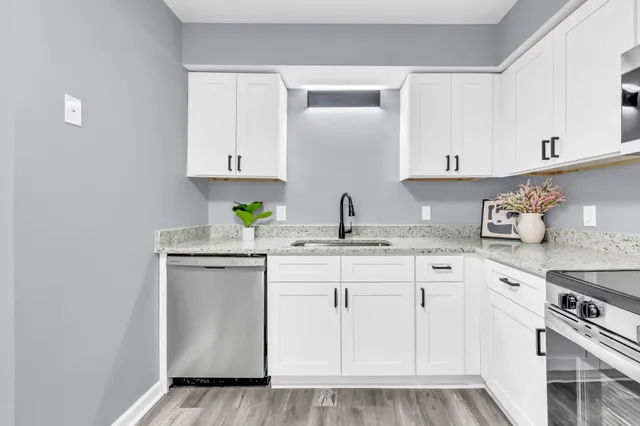 a kitchen with granite countertop a sink stainless steel appliances and white cabinets