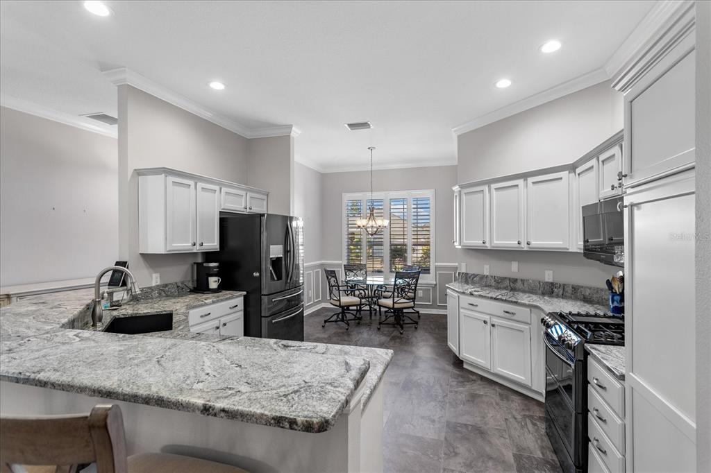566 Allenwood Loop The Villages, FL 32162 - Photo 12 of 32 a kitchen with stainless steel appliances granite countertop a sink stove and refrigerator