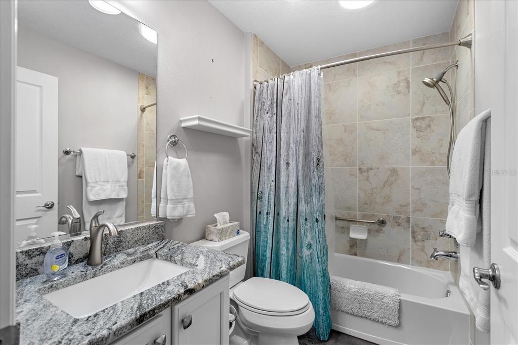 566 Allenwood Loop The Villages, FL 32162 - Photo 27 of 32 a bathroom with a granite countertop sink toilet and shower