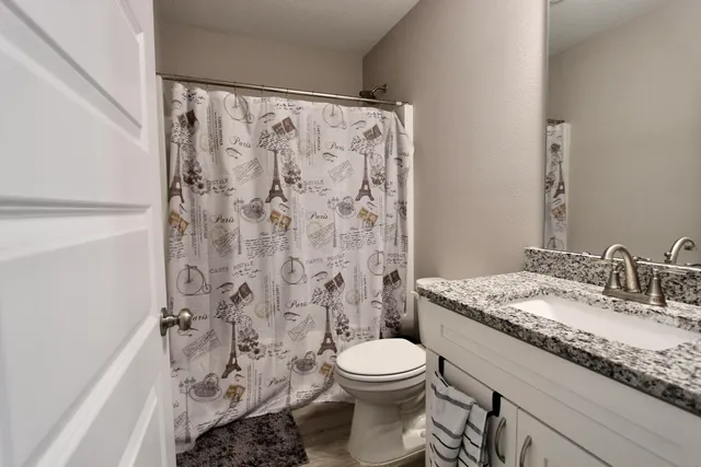 a bathroom with a granite countertop toilet a sink and a shower