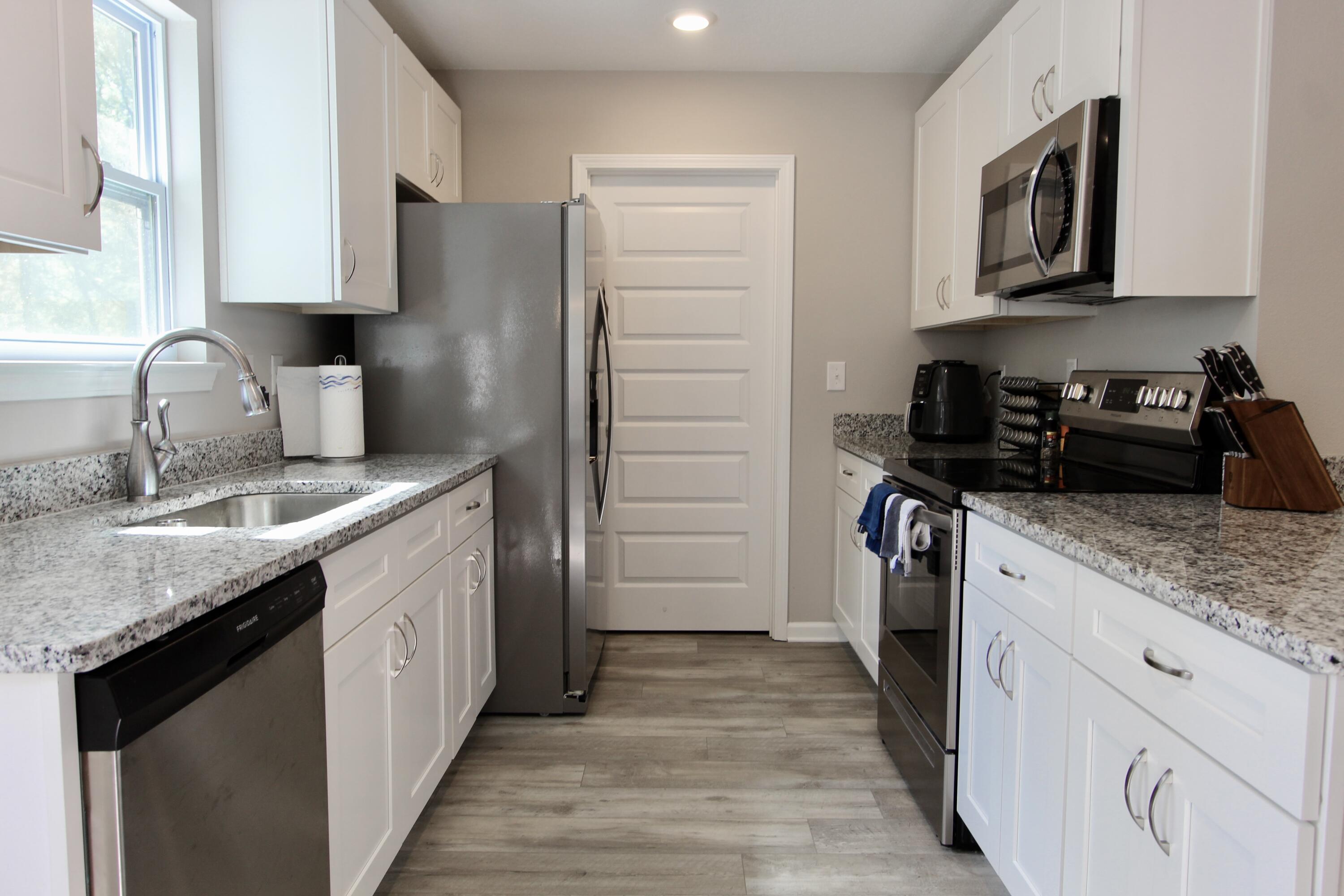 102 Windsor Drive Crestview, FL 32539 - Photo 6 of 26 a kitchen with a sink dishwasher a refrigerator and cabinets
