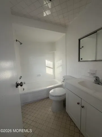 a bathroom with a granite countertop toilet a sink a mirror and vanity
