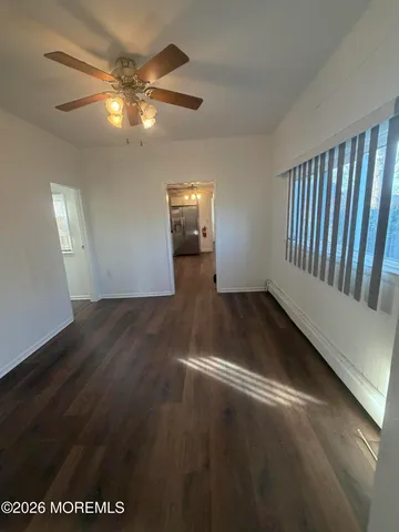 an empty room with wooden floor fan and windows