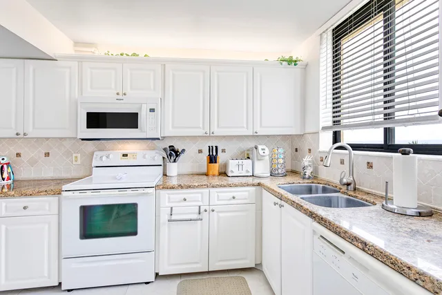 a kitchen with granite countertop white cabinets and white appliances