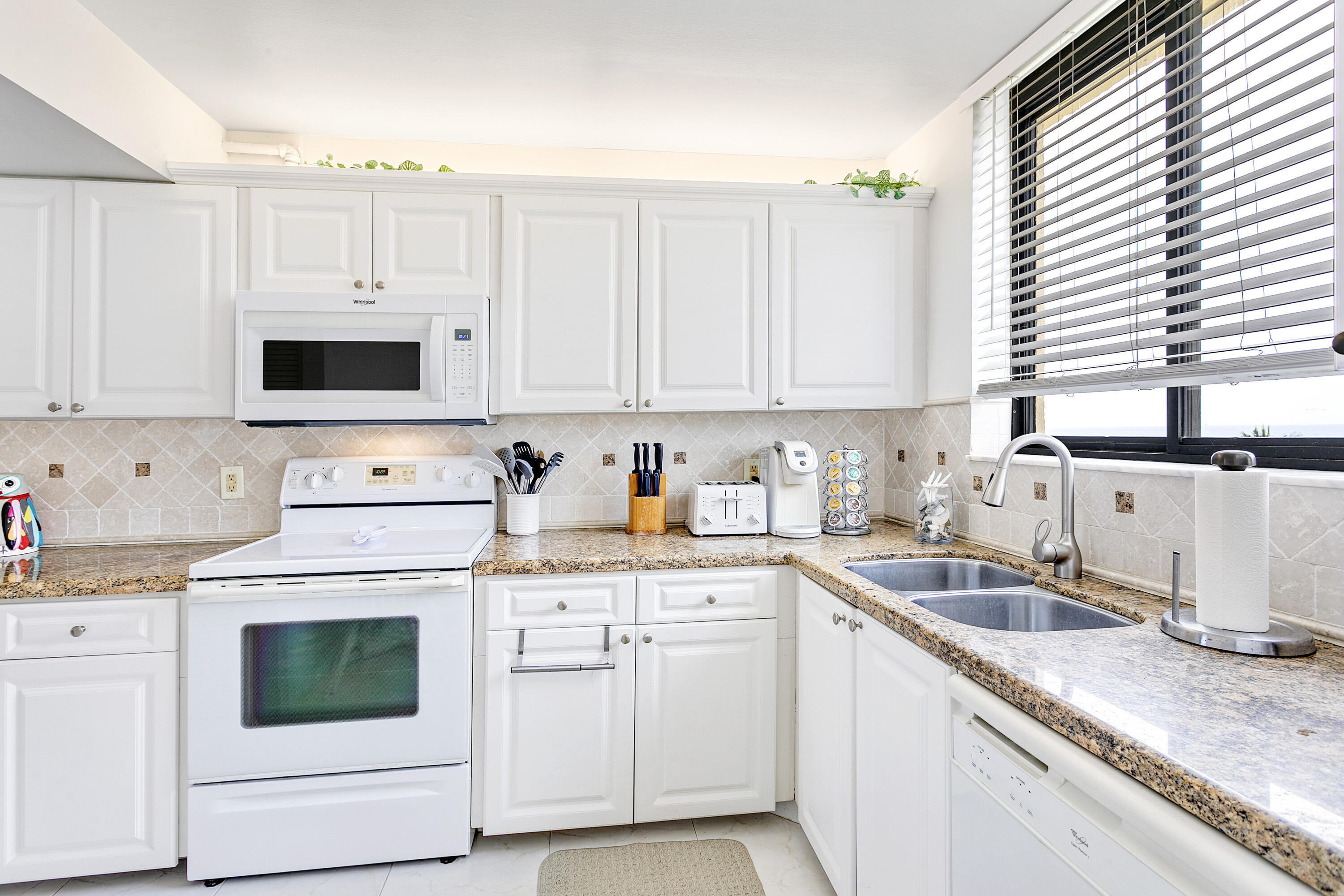 100 Ocean Trail Way, Unit 501 Jupiter, FL 33477 - Photo 9 of 30 a kitchen with granite countertop white cabinets and white appliances