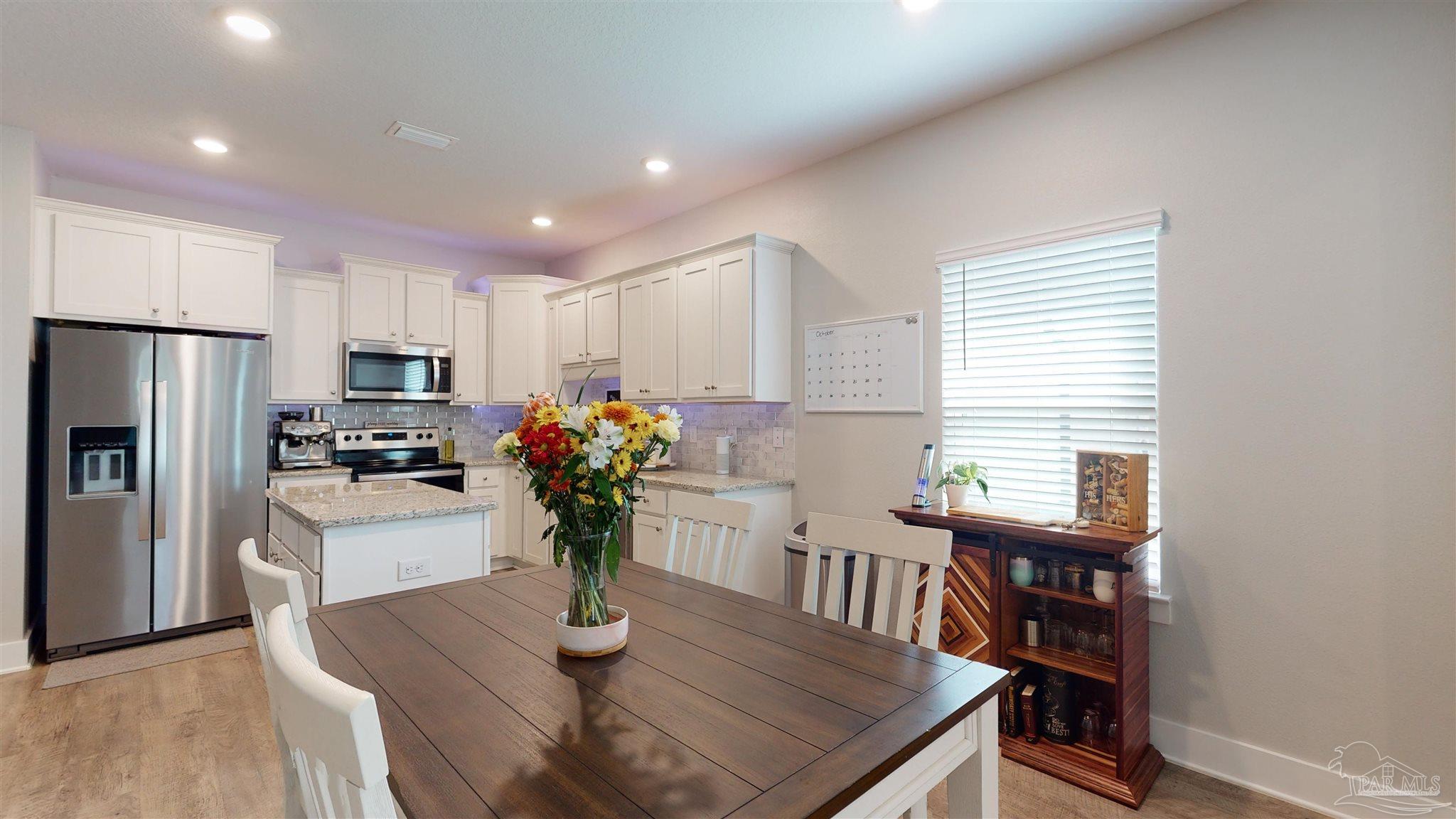 5789 Conley Court Milton, FL 32571 - Photo 16 of 50 a kitchen with stainless steel appliances granite countertop sink refrigerator dining table and chairs