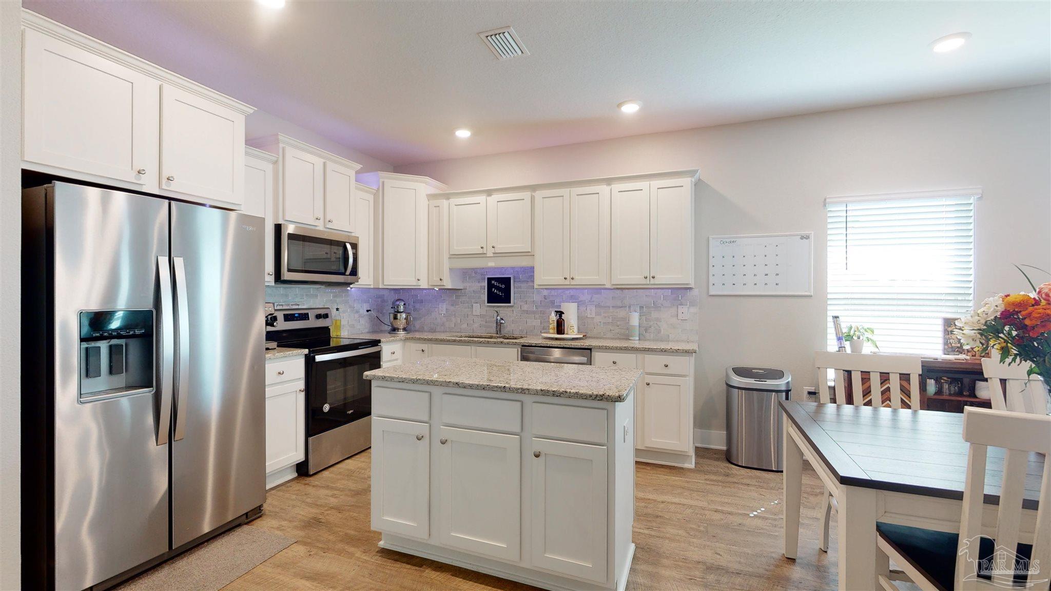 5789 Conley Court Milton, FL 32571 - Photo 20 of 50 a kitchen with a refrigerator a stove cabinets dining table and chairs