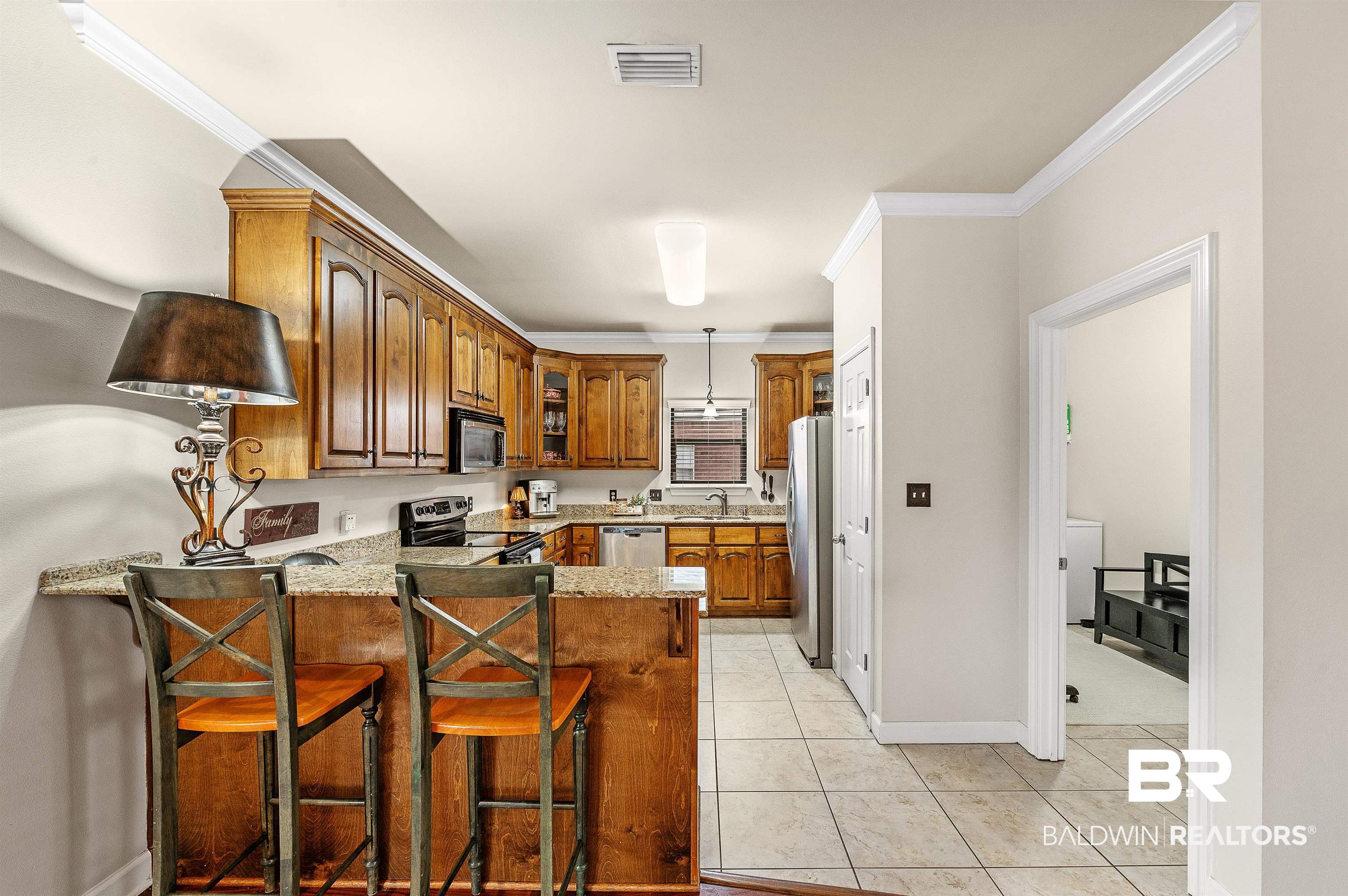 9376 Sable Court Daphne, AL 36526 - Photo 21 of 46 Kitchen with a kitchen breakfast bar, stainless steel appliances, ornamental molding, kitchen peninsula, and light stone counters