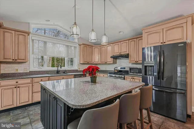 a kitchen with granite countertop a center island stainless steel appliances cabinets and a window