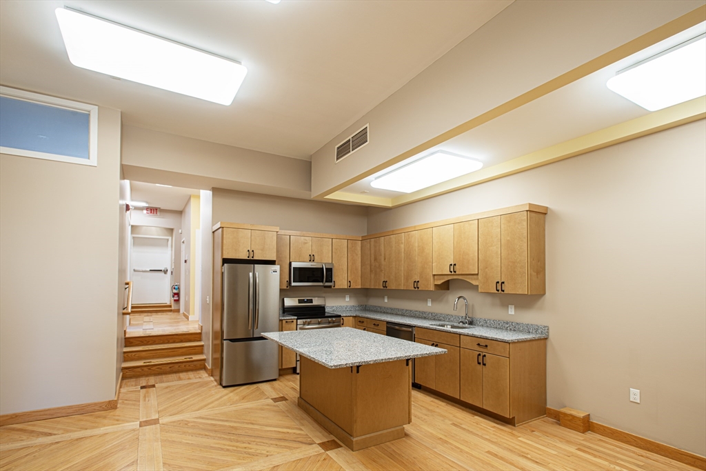 a kitchen with granite countertop a refrigerator and a stove top oven