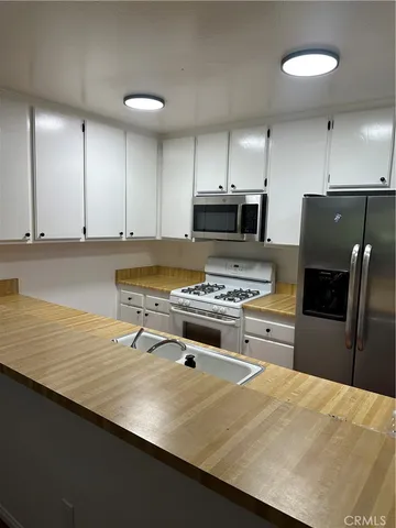 a kitchen with kitchen island a stove a refrigerator and a sink