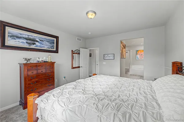 a bedroom with a bed and a lamp on dresser