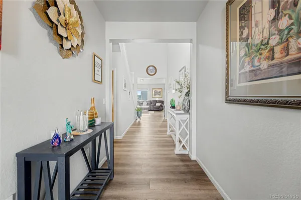 a view of a hallway to a livingroom with wooden floor and stairs