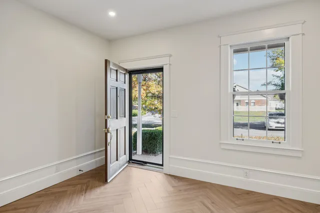 a view of an empty room with window and wooden floor
