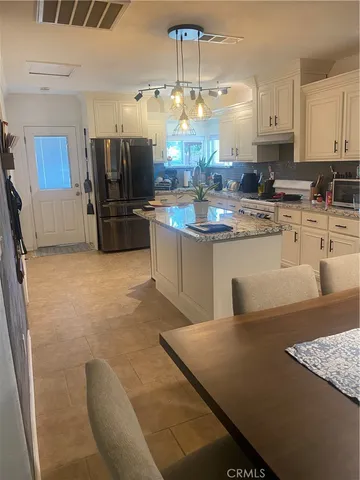 a kitchen with kitchen island granite countertop a sink cabinets and stainless steel appliances