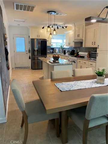 a kitchen with granite countertop a table chairs microwave and cabinets