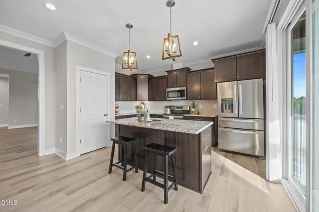 a kitchen with kitchen island a refrigerator a stove a sink and a refrigerator with wooden floor