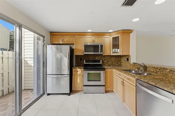 a kitchen with stainless steel appliances granite countertop a refrigerator sink stove and microwave