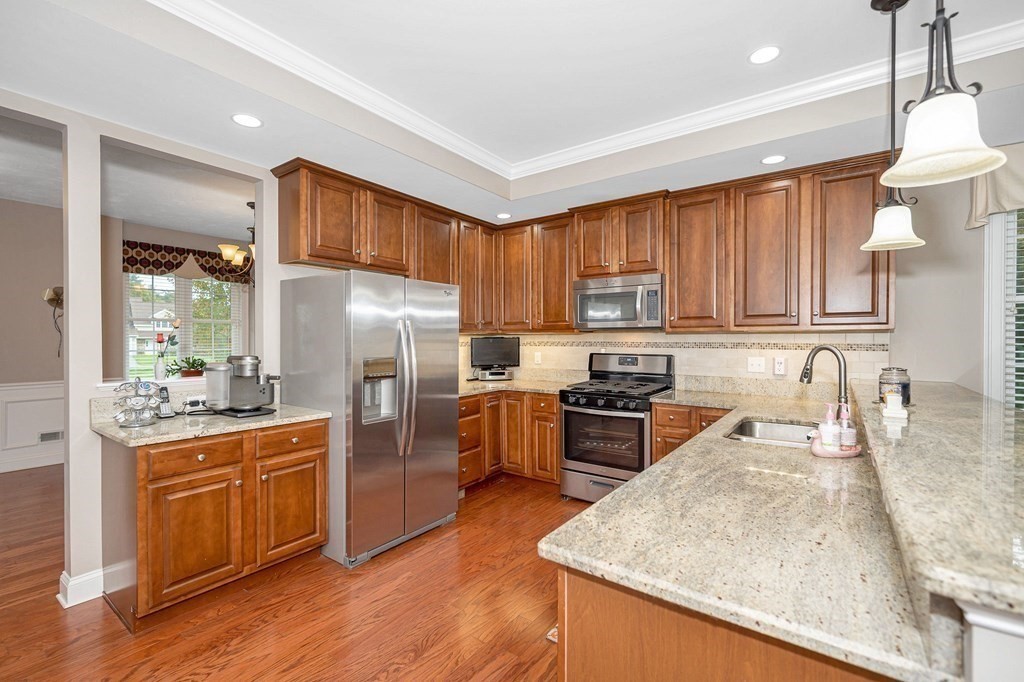 53 Baldwin Road, Unit 1701 Billerica, MA 01821 - Photo 9 of 42 a kitchen with granite countertop a stove top oven a sink dishwasher a refrigerator and cabinets with wooden floor