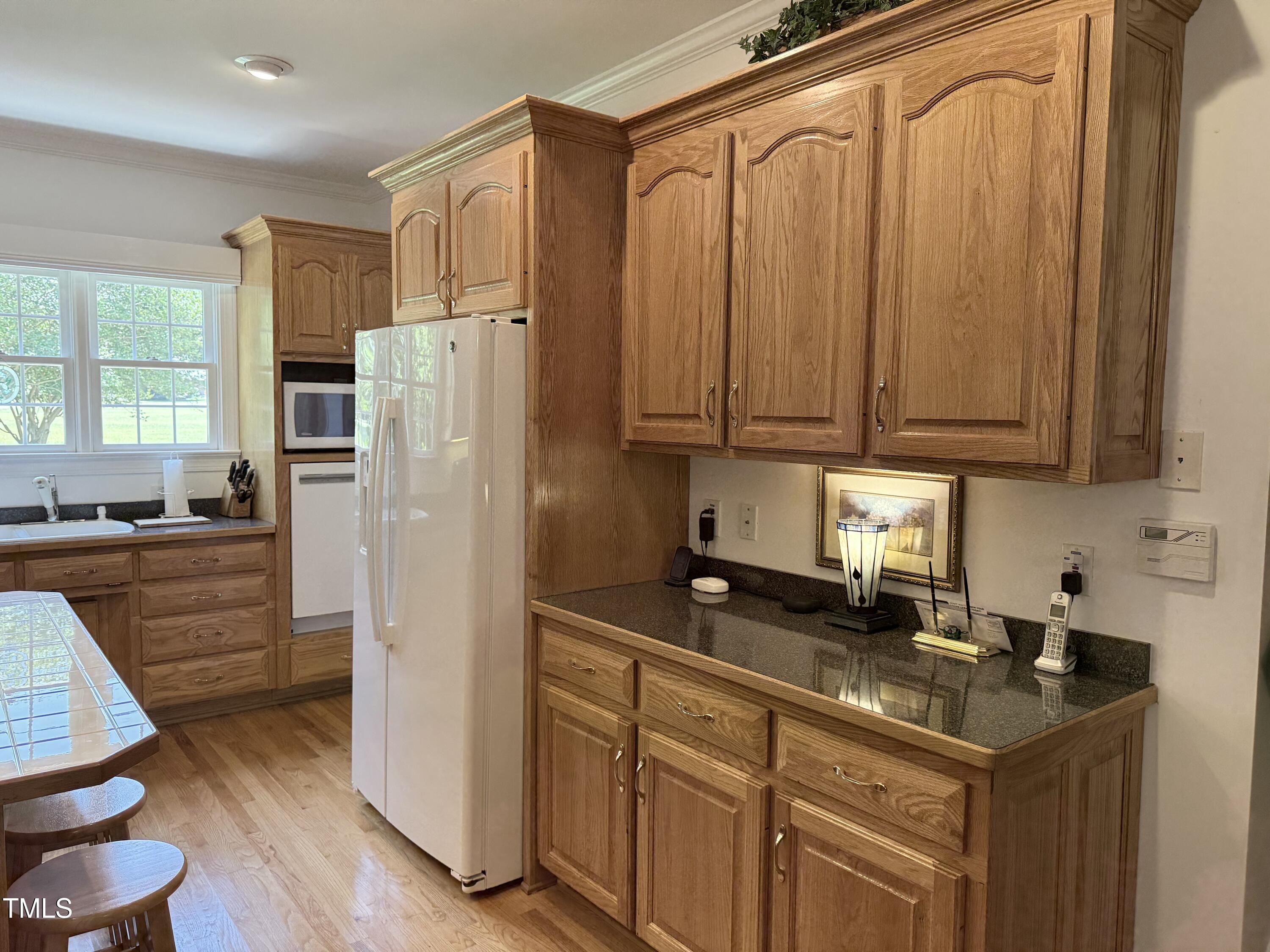 8733 Crowder Road Raleigh, NC 27603 - Photo 22 of 50 a kitchen with stainless steel appliances granite countertop a refrigerator a sink dishwasher and wooden cabinets with wooden floor