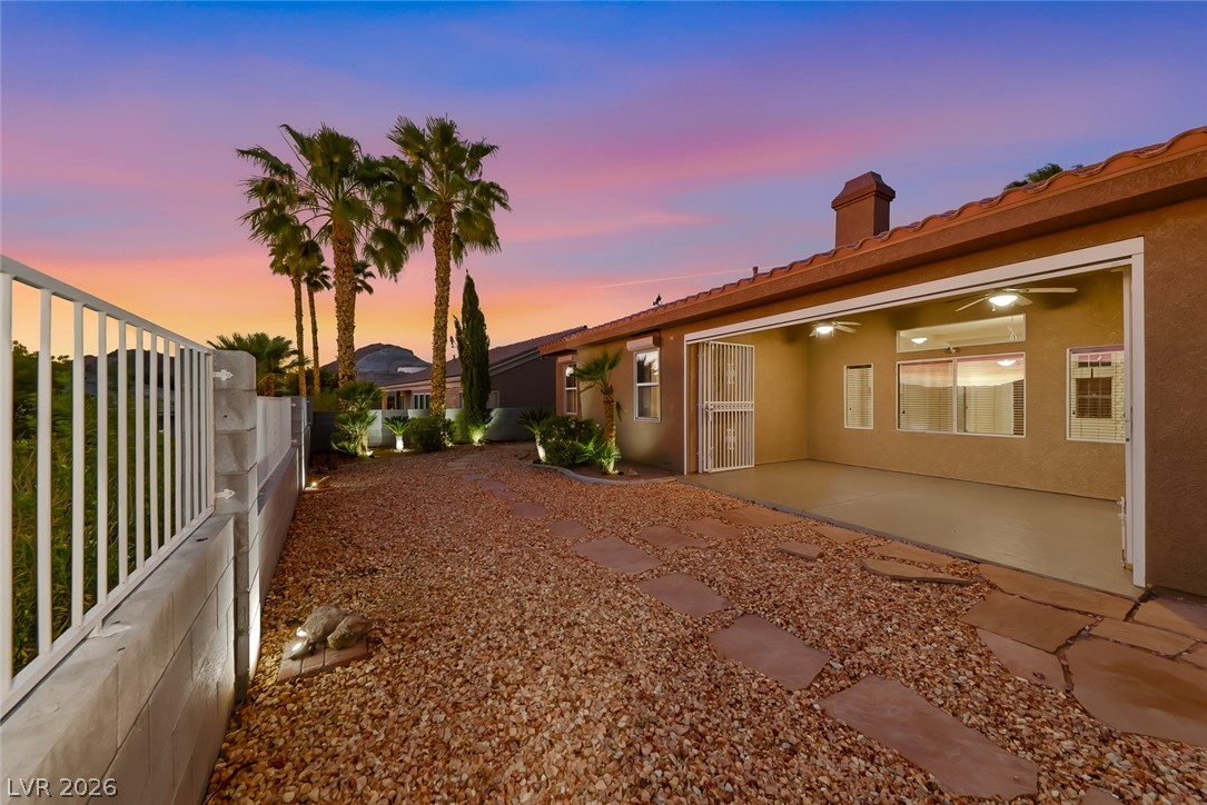 1104 Norellat Road Henderson, NV 89011 - Photo 42 of 52 A spacious covered patio overlooks a desert-landscaped yard lined with palm trees.