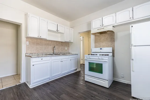 a kitchen with stainless steel appliances white cabinets and wooden floors