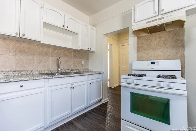 a kitchen with granite countertop white cabinets and white appliances