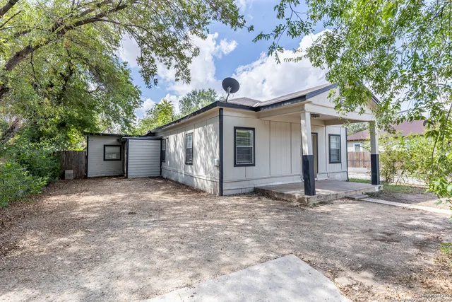 a view of a house with a yard and large tree