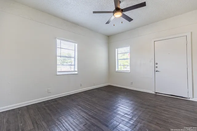 a view of an empty room with wooden floor and a window