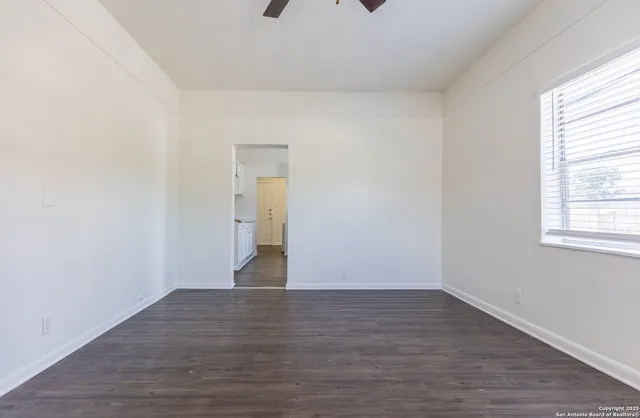 a view of an empty room with wooden floor and a window