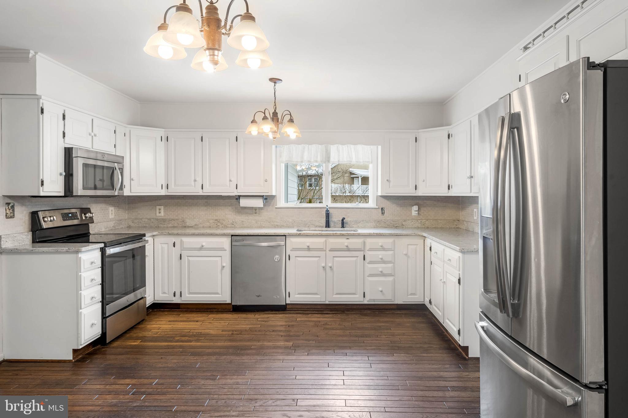 27 Devries Circle Lewes, DE 19958 - Photo 10 of 40 a kitchen with granite countertop a refrigerator oven a sink and white cabinets