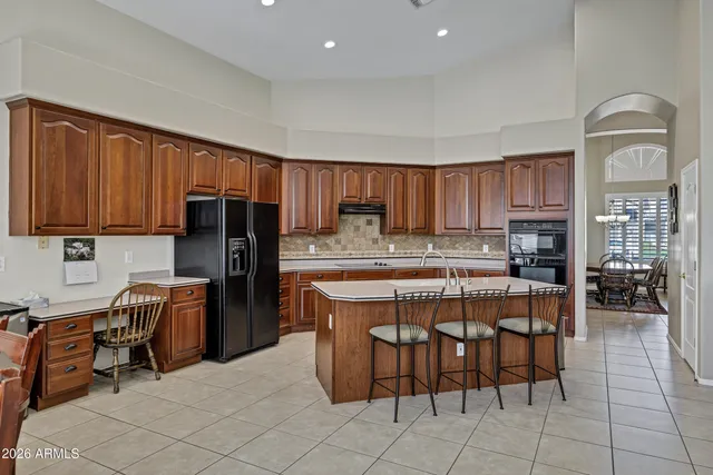 a kitchen with stainless steel appliances granite countertop a stove top oven a refrigerator a sink a dining table and chairs